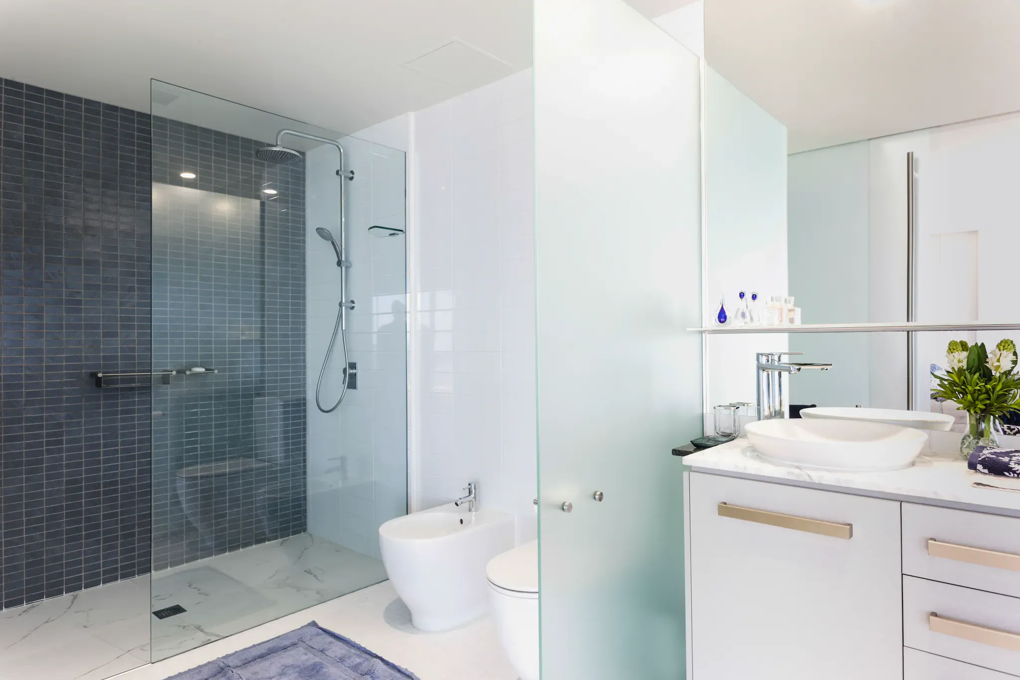 Modern bathroom featuring a glass shower door, elegant table top, and stylish mirrors, showcasing custom glass and tempered glass design elements.