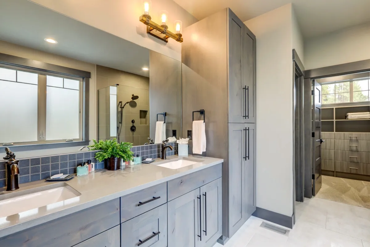 Contemporary bathroom featuring custom mirrors, a sleek countertop, and a shower area with tempered glass doors, showcasing a modern design with elegant finishes.