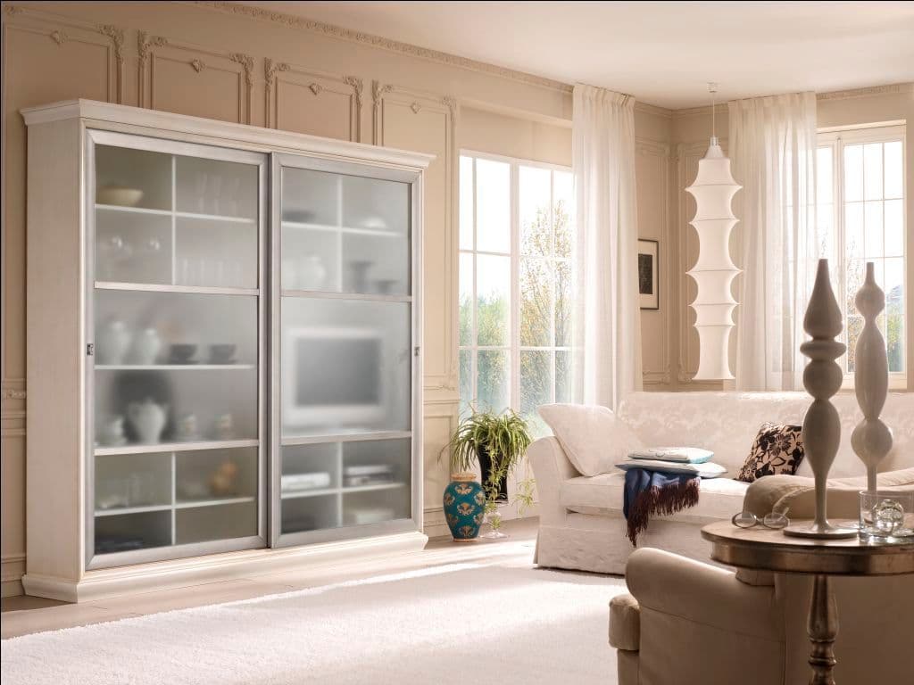 Sliding glass cabinet with frosted panels in a bright living room, showcasing custom glass design. Ideal for displaying elegant table tops and mirrors, emphasizing tempered glass and a sophisticated beveled glass edge.