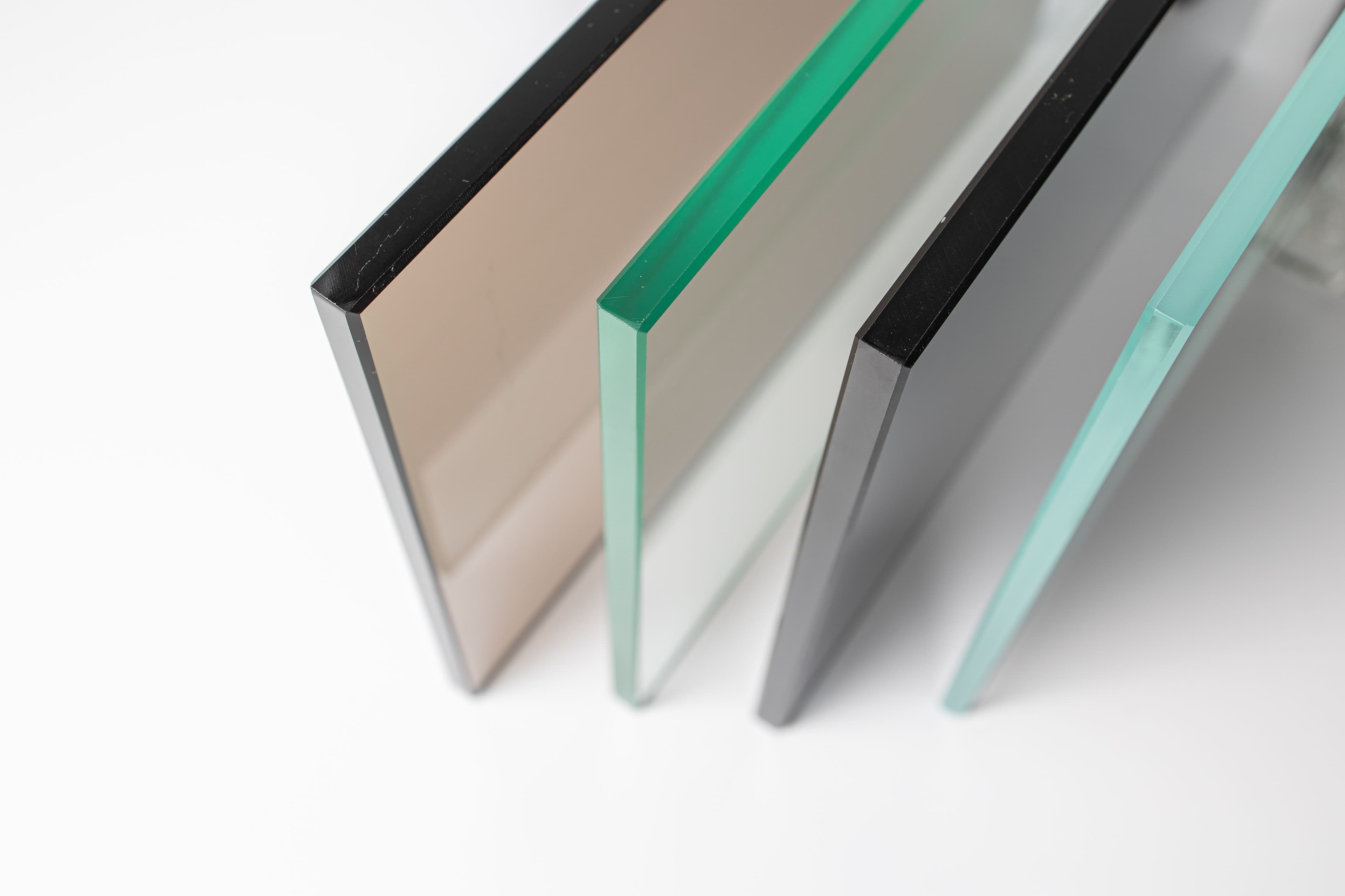 Close-up of various types of glass panels including tempered glass and beveled glass edge, showcasing options for custom shower doors, table tops, and mirrors.