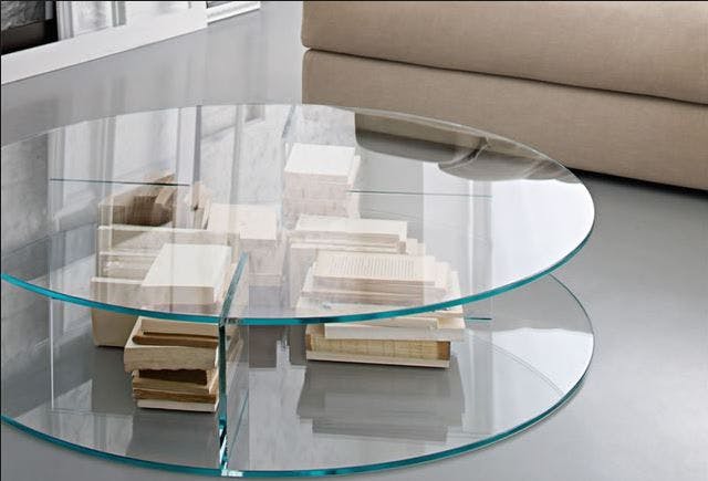 Round clear glass coffee table with shelves holding books