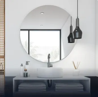 Modern bathroom featuring a large round mirror, stylish lighting, and a sleek sink, showcasing custom glass designs.