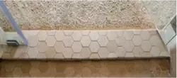 Hexagonal tile shower threshold with custom glass shower doors showcasing tempered glass edge.