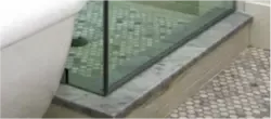 custom glass shower door with beveled glass edge alongside a modern bathtub on a stone base
