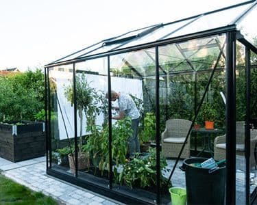 Custom glass greenhouse featuring tempered glass panels and sleek design, ideal for showcasing plants and enhancing outdoor spaces.
