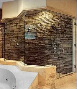 Custom tempered glass shower doors with a beveled glass edge, featuring a modern stone wall design and elegant fixtures.