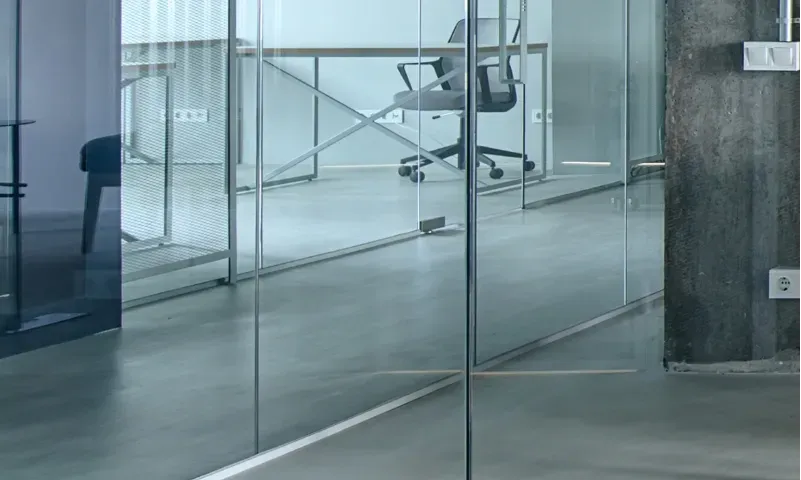 Modern office space featuring custom glass shower doors with tempered glass and sleek beveled glass edges, complemented by a minimalist design and natural light.