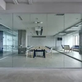 Modern conference room with custom glass walls, featuring tempered glass for transparency and beveled glass edges, enhancing the stylish interior design.