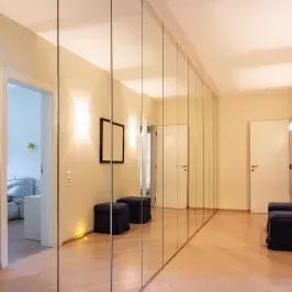 Custom mirrors with beveled glass edges in a modern hallway, showcasing sleek design elements for shower doors and tempered glass solutions.
