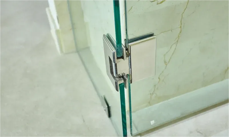 Custom glass shower door with a tempered glass panel and sleek metal hinge, showcasing quality craftsmanship in modern design.