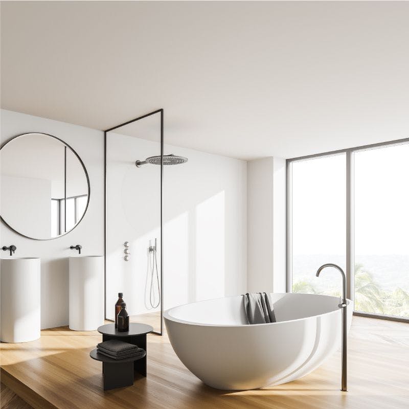 Spacious modern bathroom with glass panel, wooden floor and large tub for a relaxing soak
