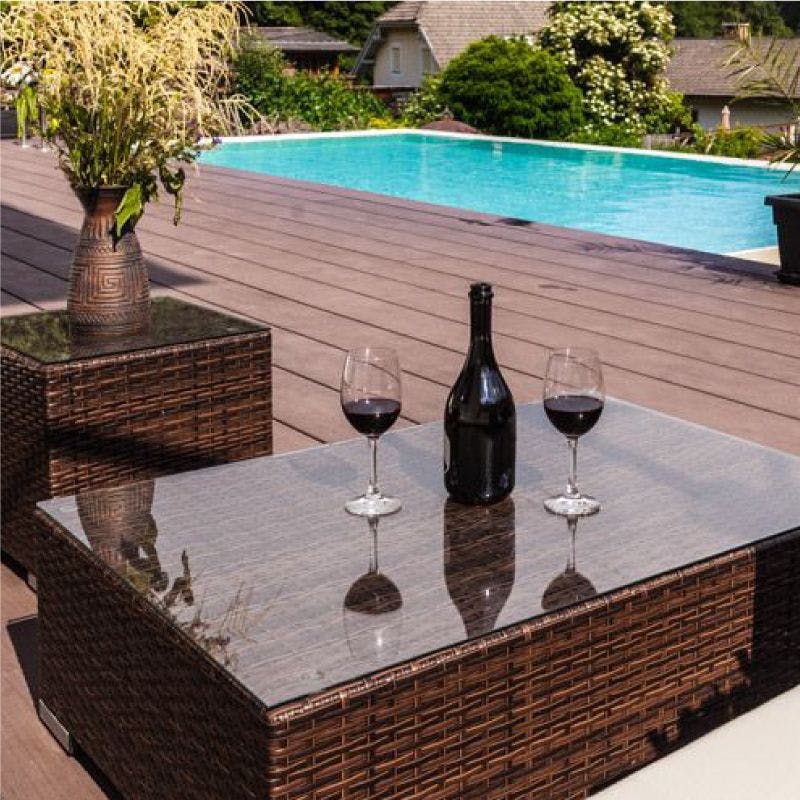 A patio glass table top adorned with two wine glasses and a bottle of wine