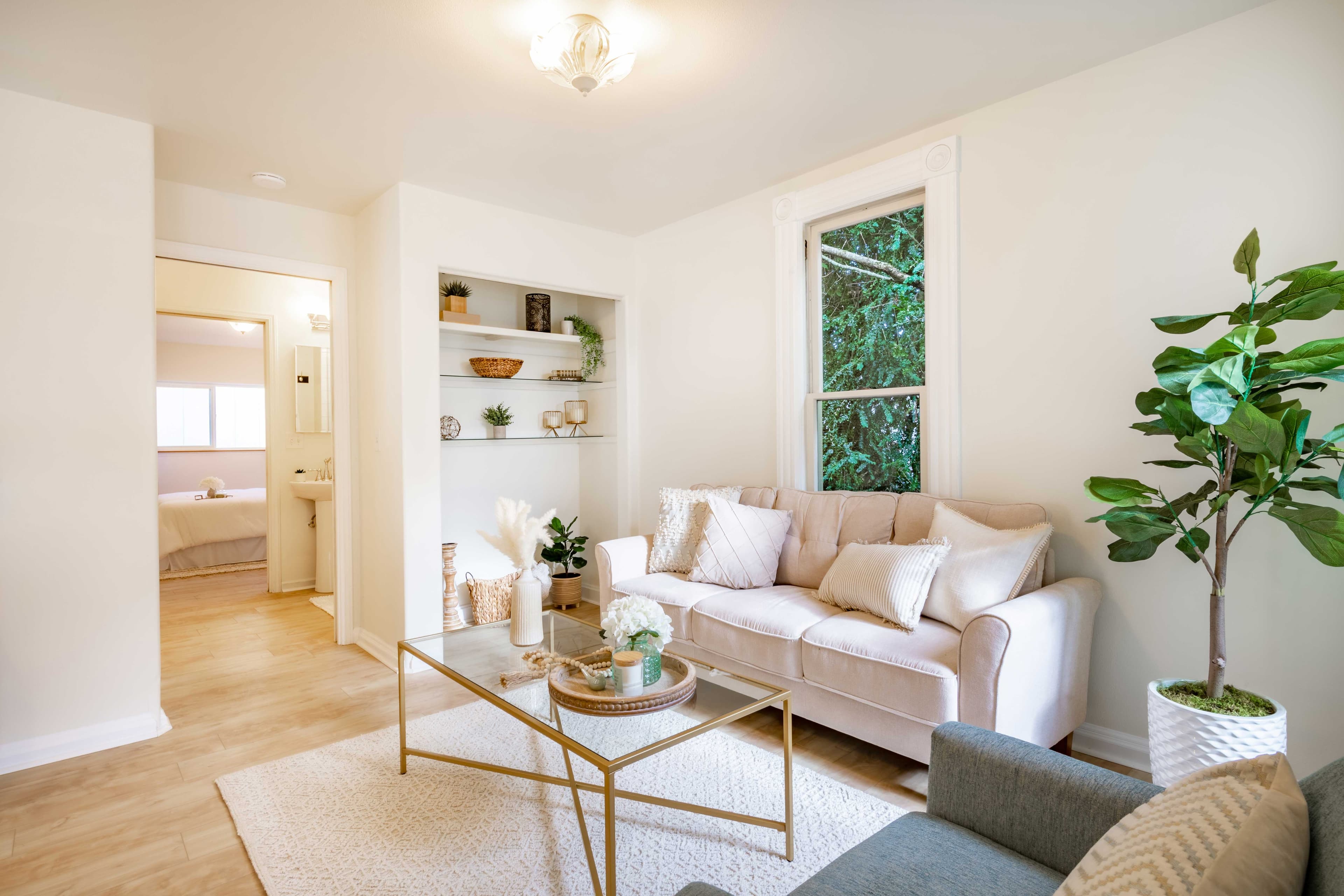 Living room featuring comfortable seating, decorative accents, and natural light, highlighting custom glass decor elements like mirrors and coffee table with beveled glass edge.