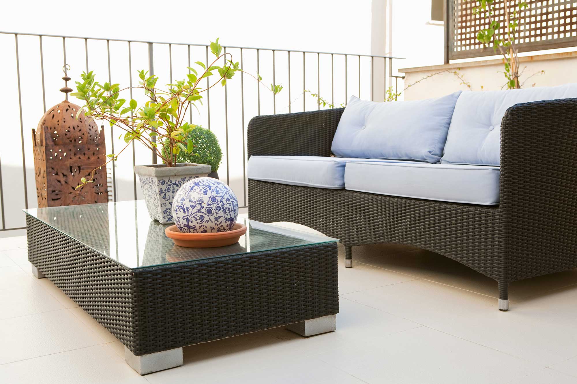 Elegant outdoor seating area featuring a glass-topped coffee table, surrounded by plants, showcasing custom glass options ideal for tables and decor.