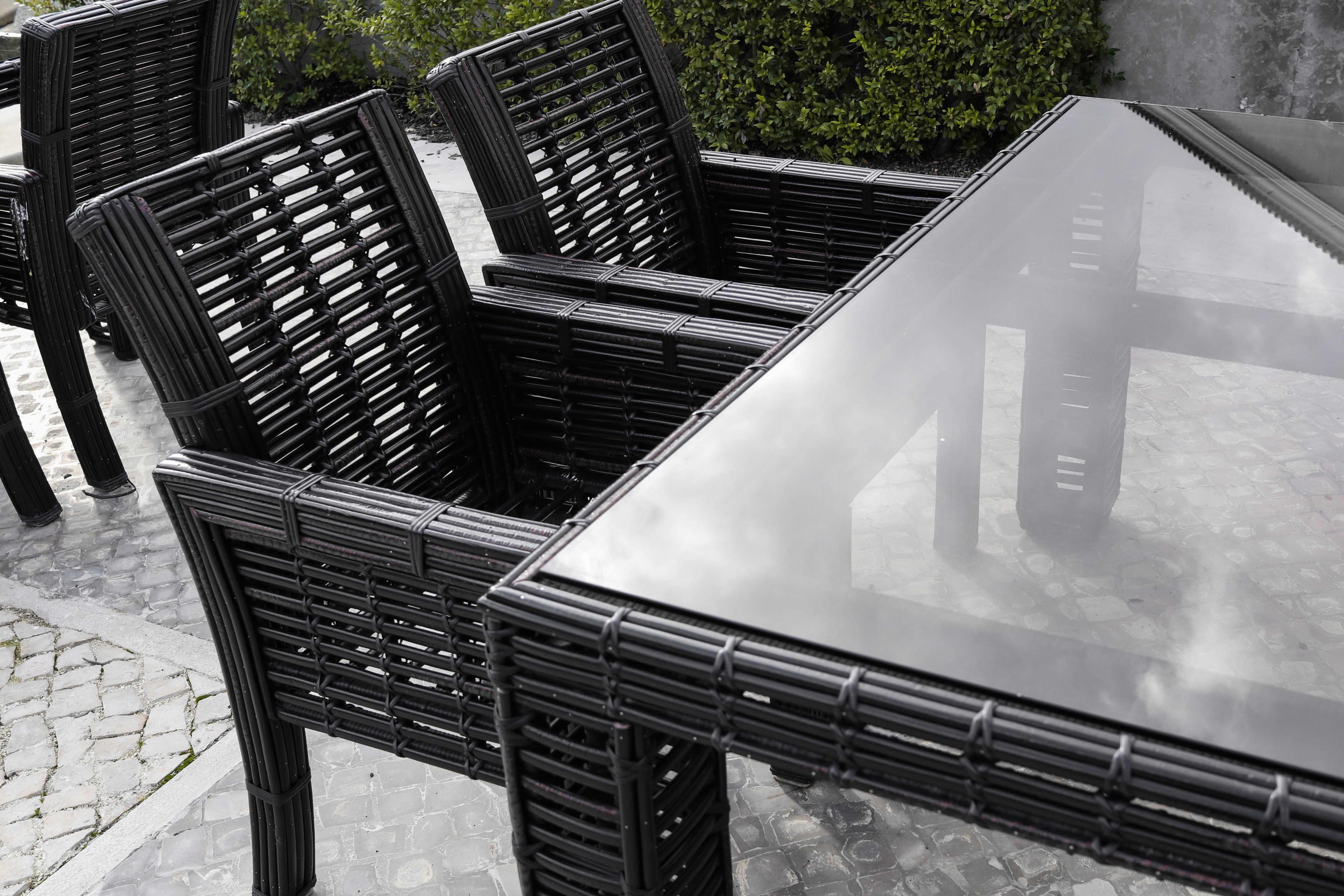 Stylish outdoor table with a sleek tempered glass top, surrounded by elegant black wicker chairs, showcasing custom glass design elements for modern living spaces.