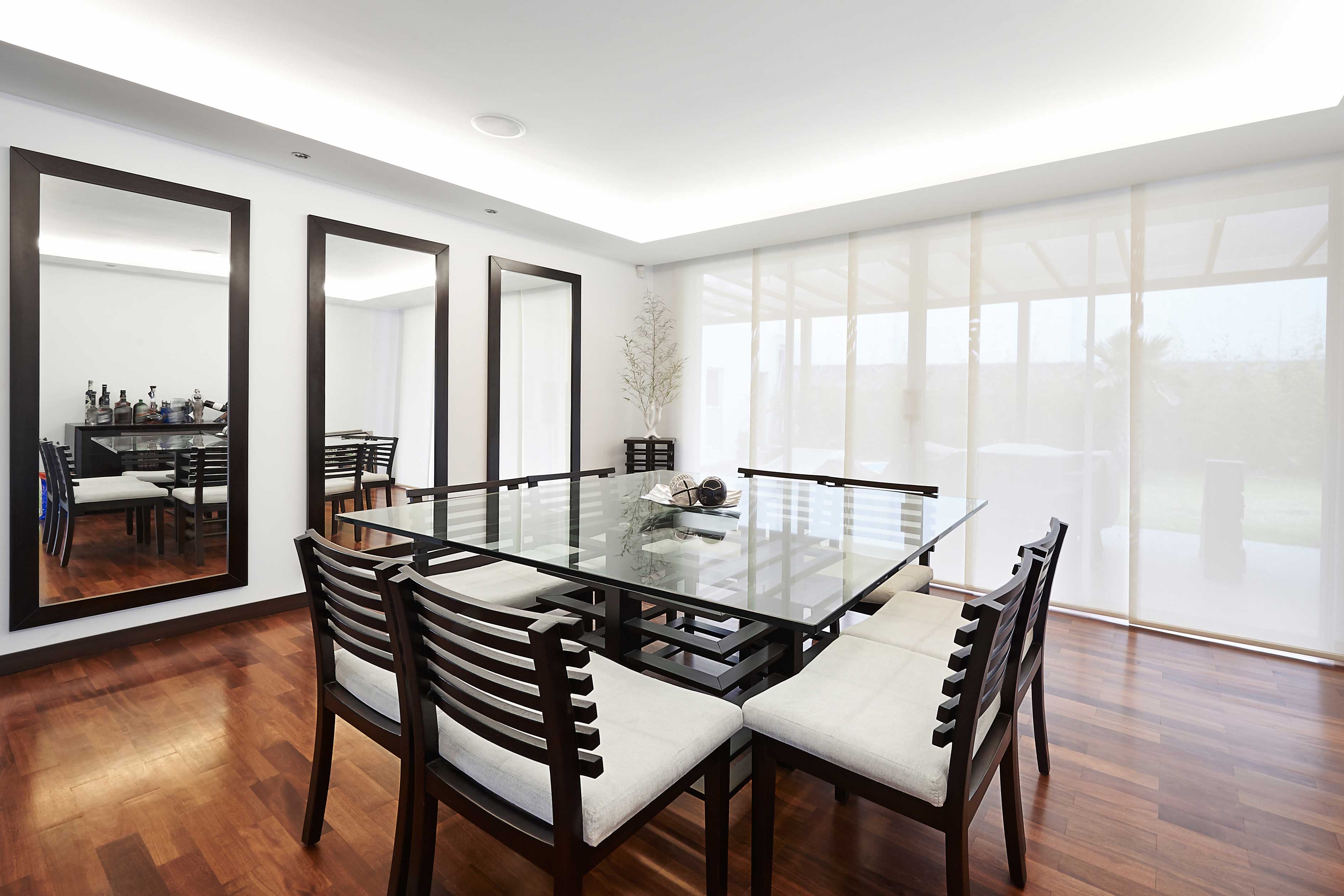 modern dining room featuring a glass table top, mirrors with beveled edges, and a sleek design, highlighting custom glass and tempered glass elements