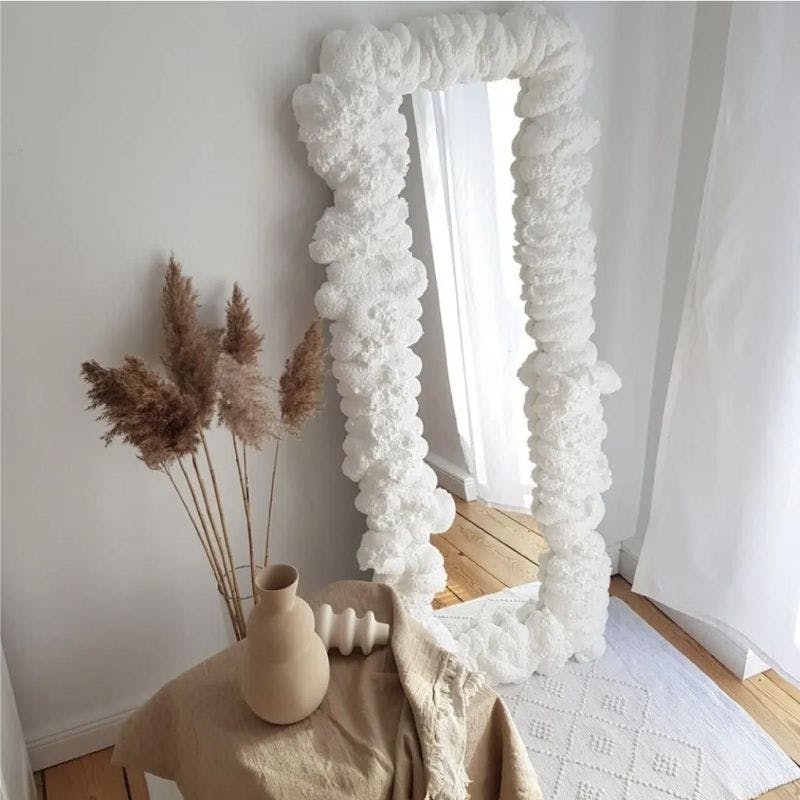 White-framed foam mirror with vase on floor