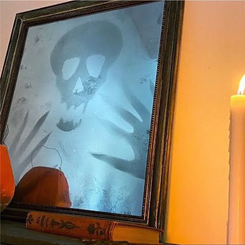 Mirror with skull and candle reflecting eerie ambiance
