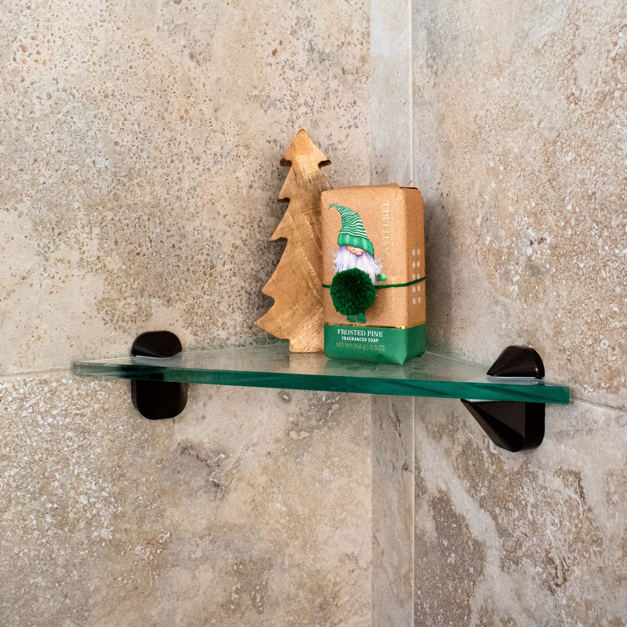 Custom glass shelf with beveled edges displaying a wooden tree and soap in a bathroom setting, showcasing versatile tempered glass solutions for shower doors and decor.