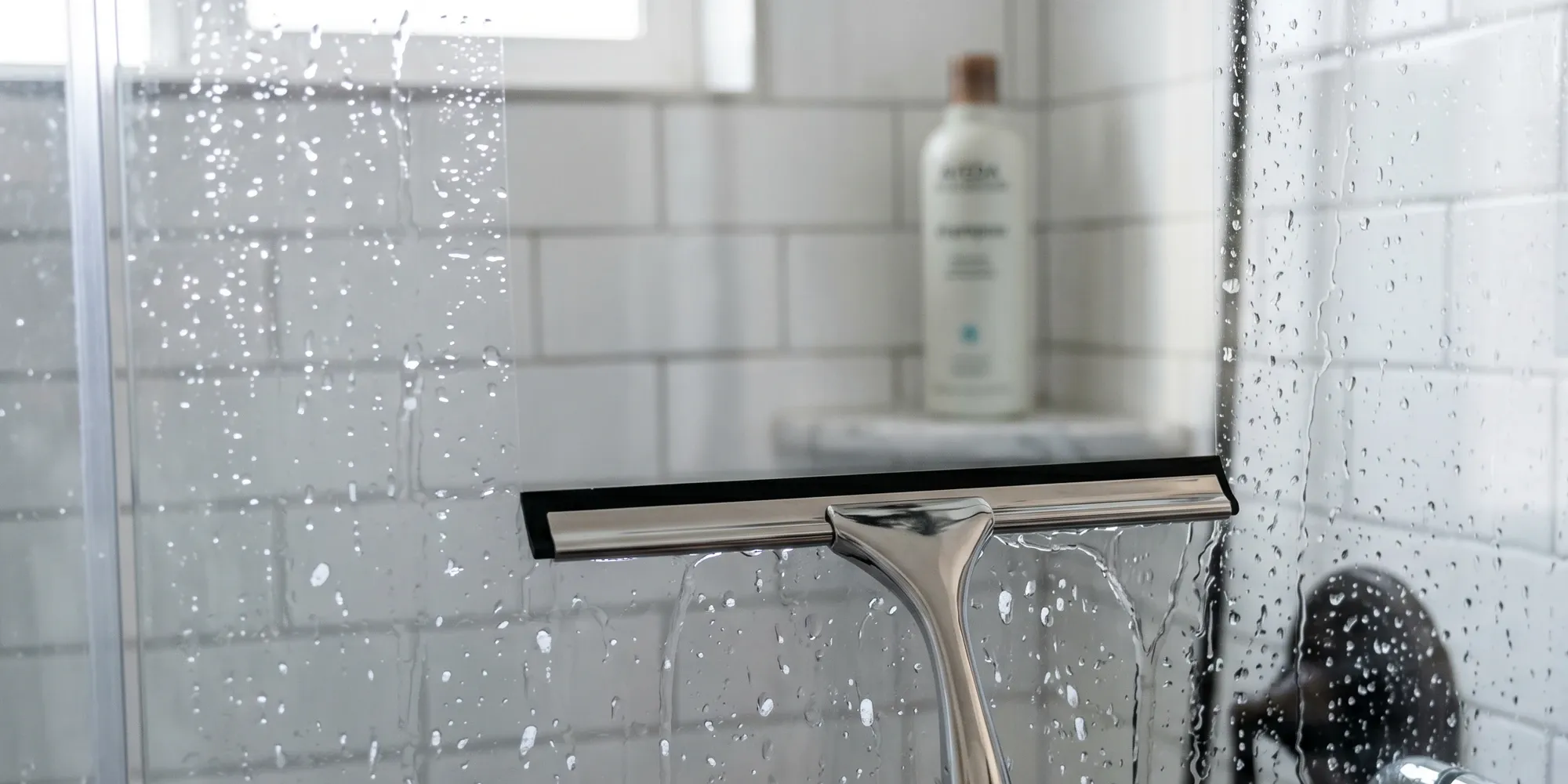 Frameless hinged shower door being cleaned with a squeegee