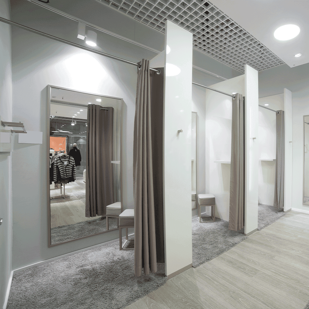 Modern fitting room featuring custom mirrors with beveled glass edges, showcasing a stylish and functional space for customers.