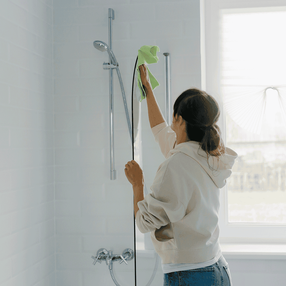 Woman cleaning a modern shower door with a cloth