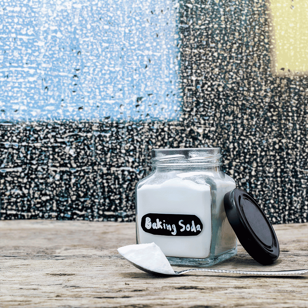 A glass jar labeled Baking Soda with a spoon beside it