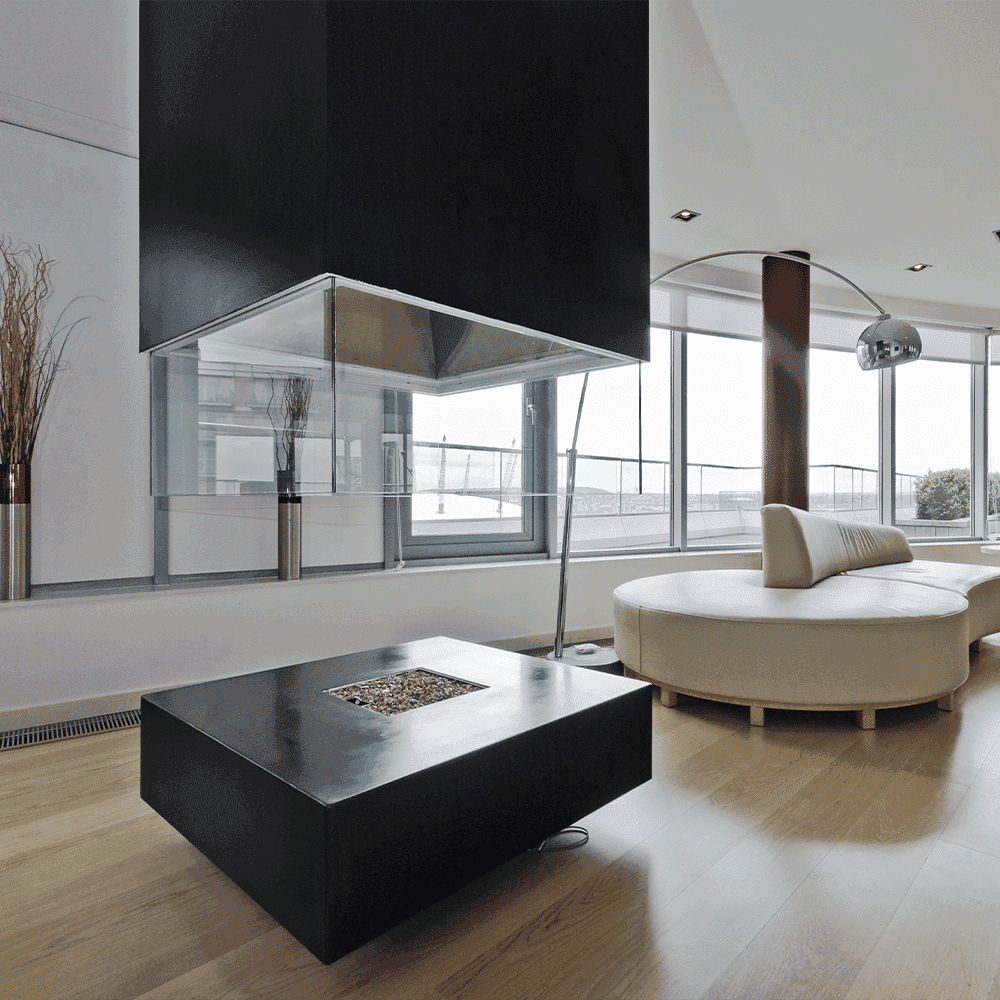 Modern living space featuring a sleek custom glass table with tempered glass edges, surrounded by stylish furniture and large windows, showcasing a minimalist aesthetic ideal for showcasing shower doors, mirrors, and table tops.