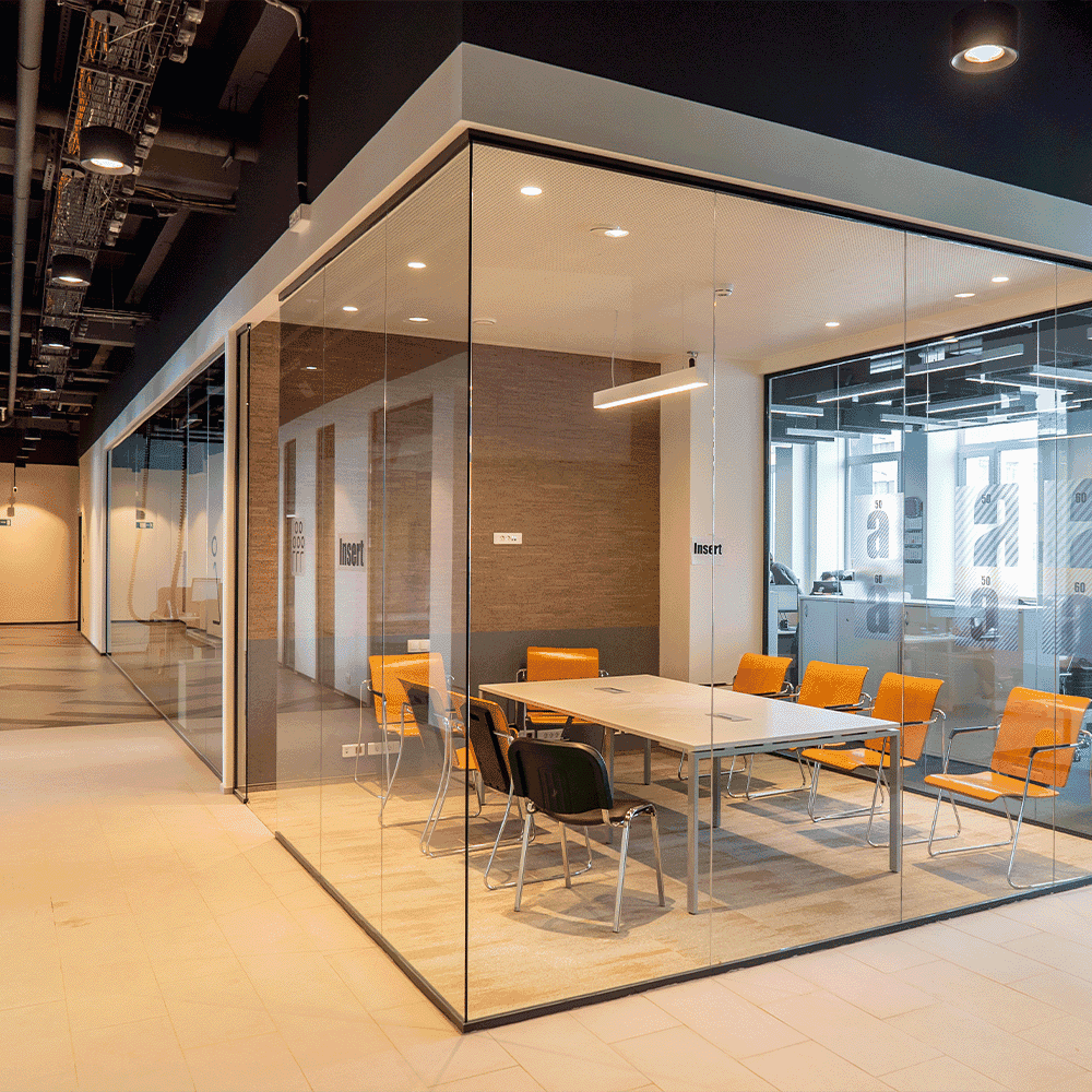 Modern conference room featuring custom glass walls, sleek tempered glass table, and stylish beveled glass edges, complemented by ergonomic chairs. Ideal for showcasing shower doors and mirrors.
