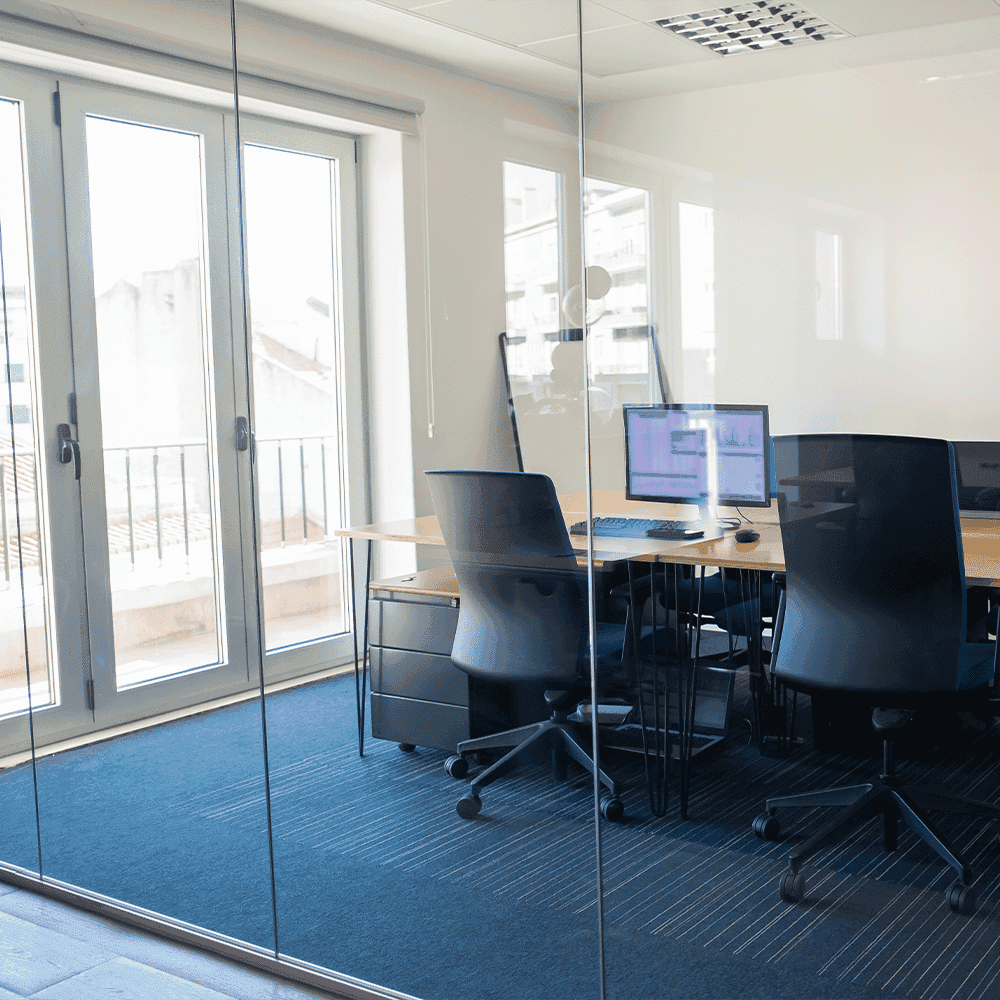 Modern office space featuring glass walls, highlighting custom glass elements and a sleek design; suitable for showcasing shower doors, table tops, mirrors, and tempered glass installations.