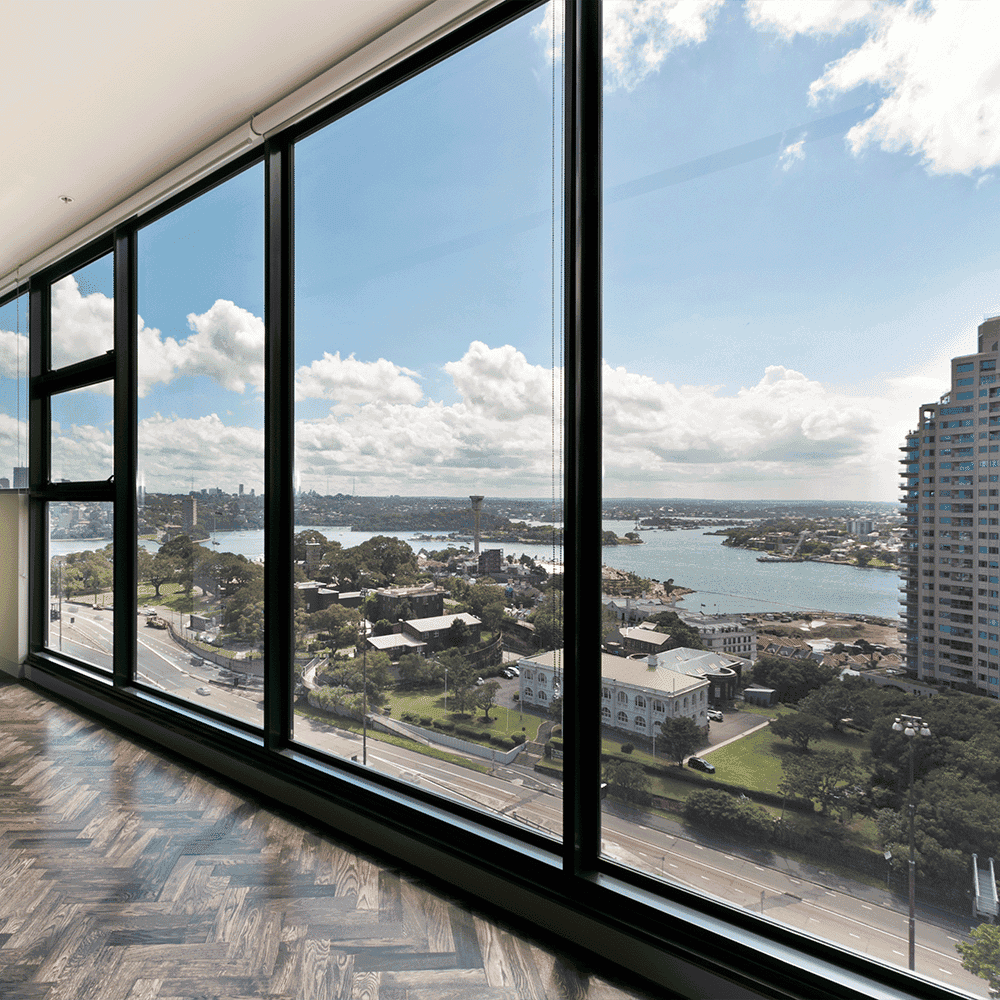 Modern interior featuring large custom glass windows with a stunning view, highlighting the use of tempered glass and sleek design elements, ideal for showcasing shower doors, table tops, and beveled glass edge applications.