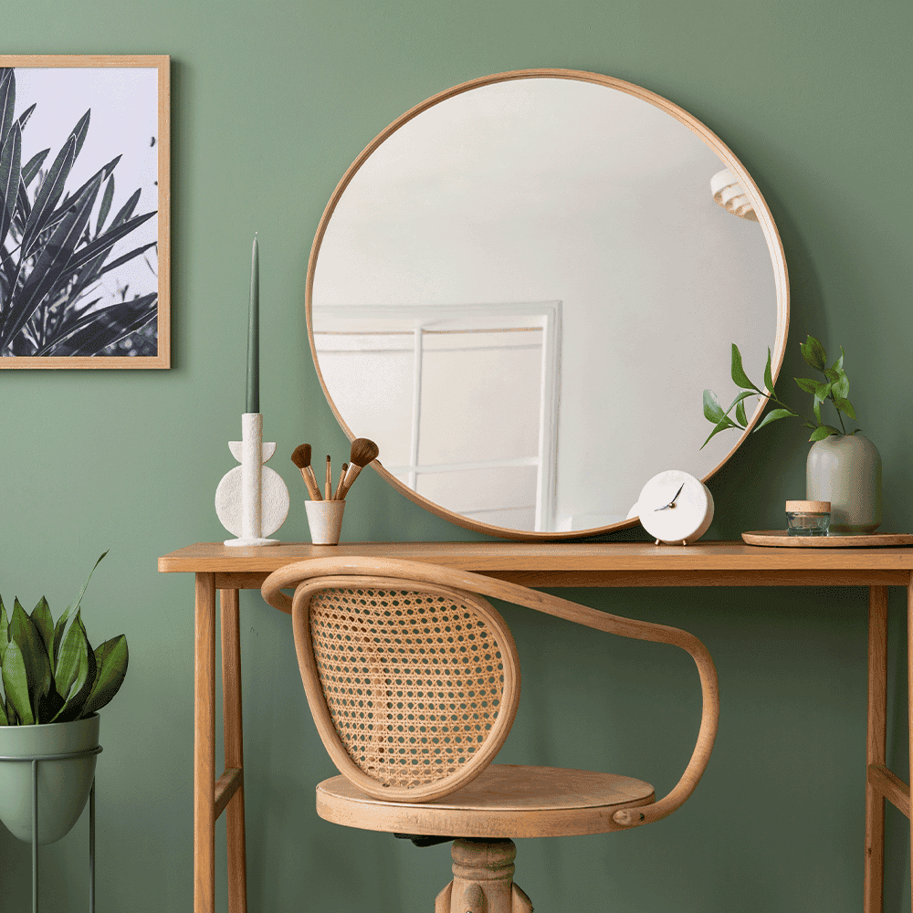 Modern interior featuring a round mirror with a wooden frame, a wooden table, and decorative elements, showcasing custom glass design.