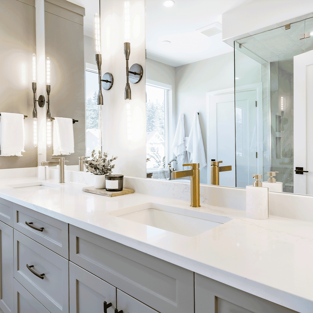 Modern bathroom featuring custom glass shower doors, a stylish beveled edge mirror, and elegant sink fixtures over a pristine white countertop, highlighting custom glass design elements.