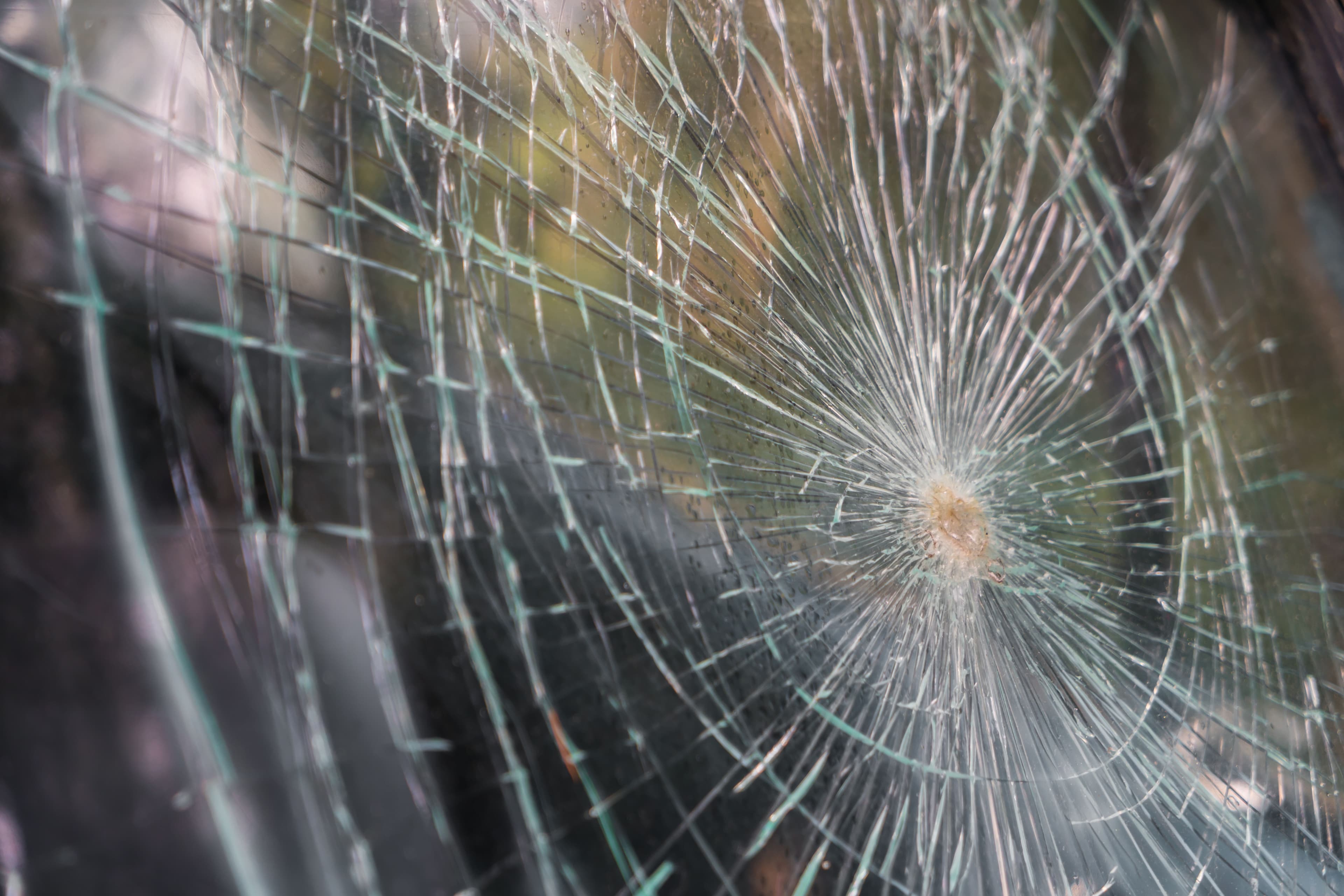 Close-up of shattered tempered glass displaying intricate crack patterns, emphasizing the importance of quality in custom glass products like shower doors, table tops, and mirrors.