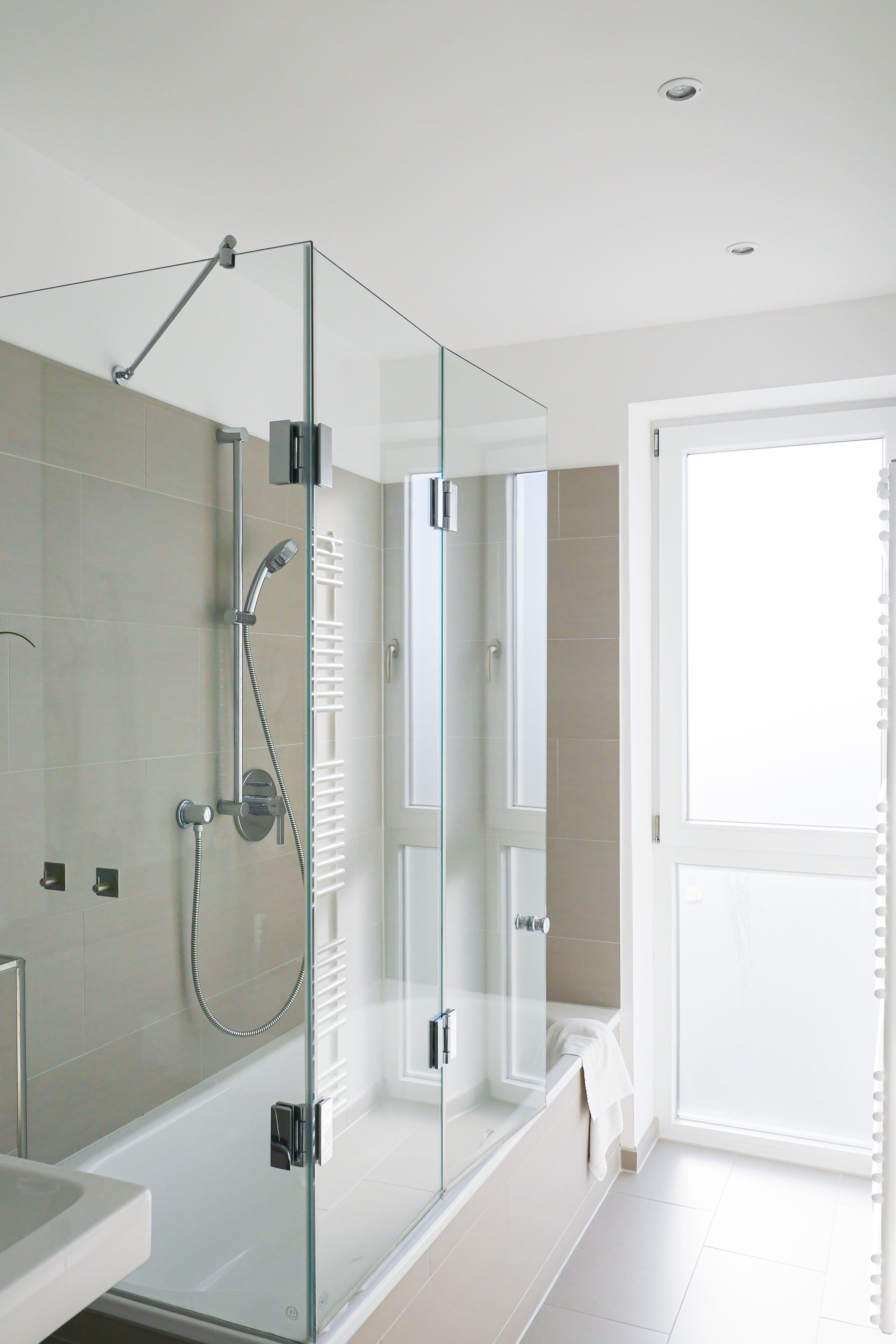 Modern bathroom featuring a sleek shower door made of tempered glass, showcasing custom glass design with seamless installation and elegant finishes.