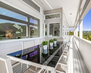 Custom glass table top on a modern patio, showcasing tempered glass with a sleek design, surrounded by contemporary furniture and scenic outdoor views.
