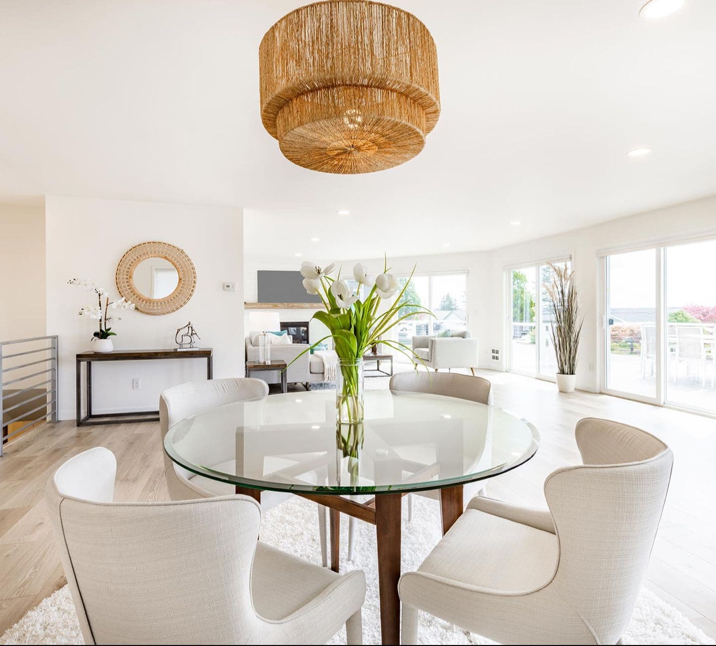 Elegant dining area featuring a round glass table with a beveled edge, surrounded by modern upholstered chairs, complemented by a decorative mirror and stylish lighting, showcasing custom glass design elements.